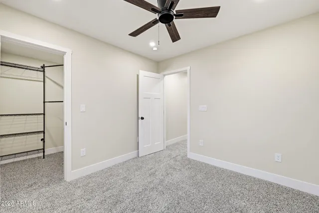 an empty room with ceiling fan and windows