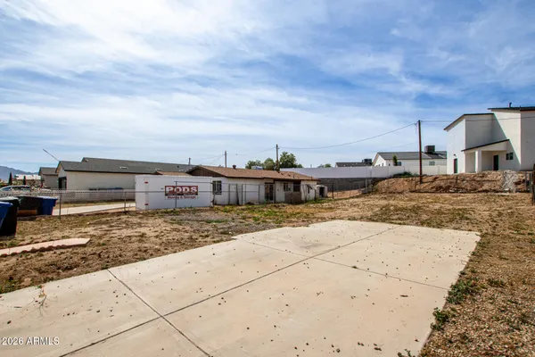 a view of a dry yard with wooden fence