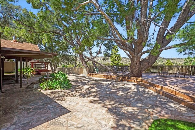 a view of a patio with table and chairs under a large tree