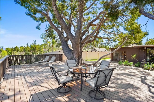 a view of a patio with table and chairs with wooden floor and fence
