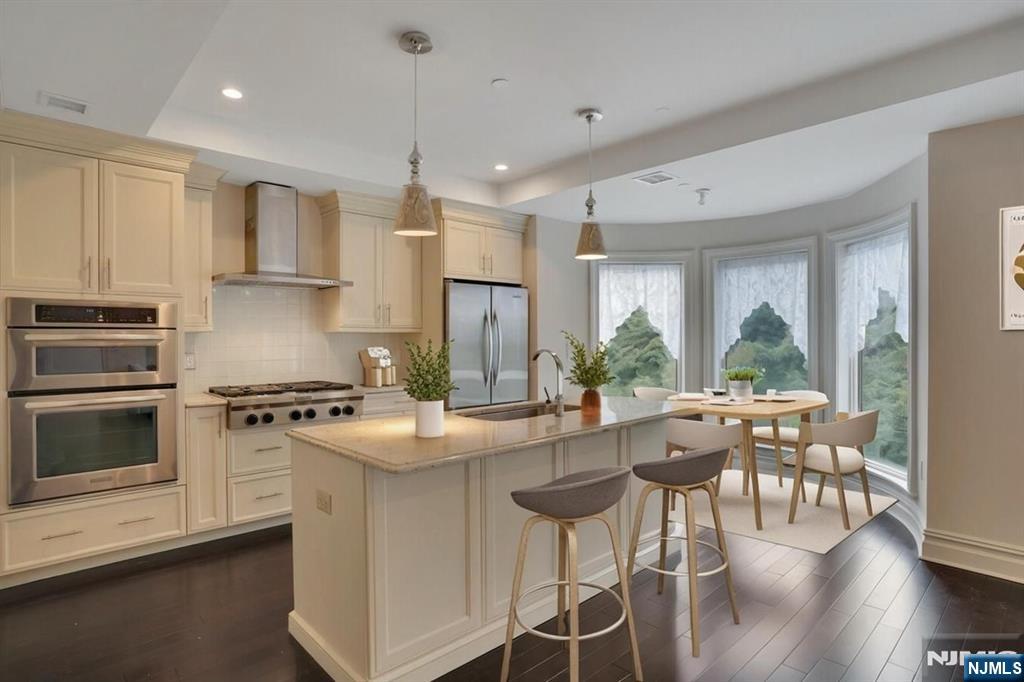 55 Eton Row Weehawken, NJ 07086 - Photo 2 of 28 a kitchen with stainless steel appliances granite countertop a stove a refrigerator a kitchen island a stove and white cabinets with wooden floor