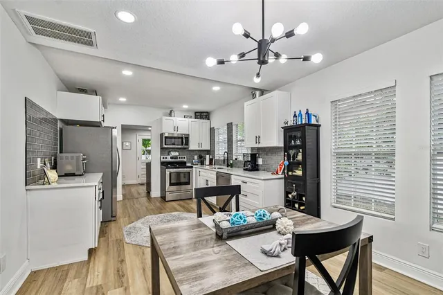 a kitchen with stainless steel appliances kitchen island granite countertop a stove top oven a sink dishwasher a refrigerator and a oven with wooden floor