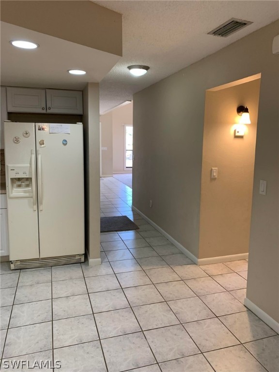 7581 Carrier Road Fort Myers, FL 33967 - Photo 3 of 14 a view of a refrigerator in kitchen and an empty room in wooden floor