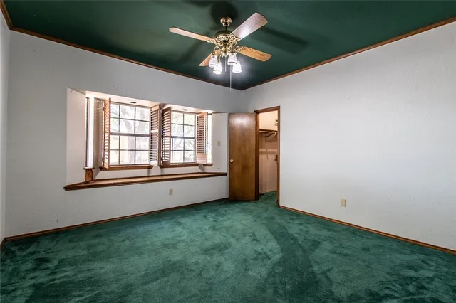 a view of an empty room with window and chandelier fan