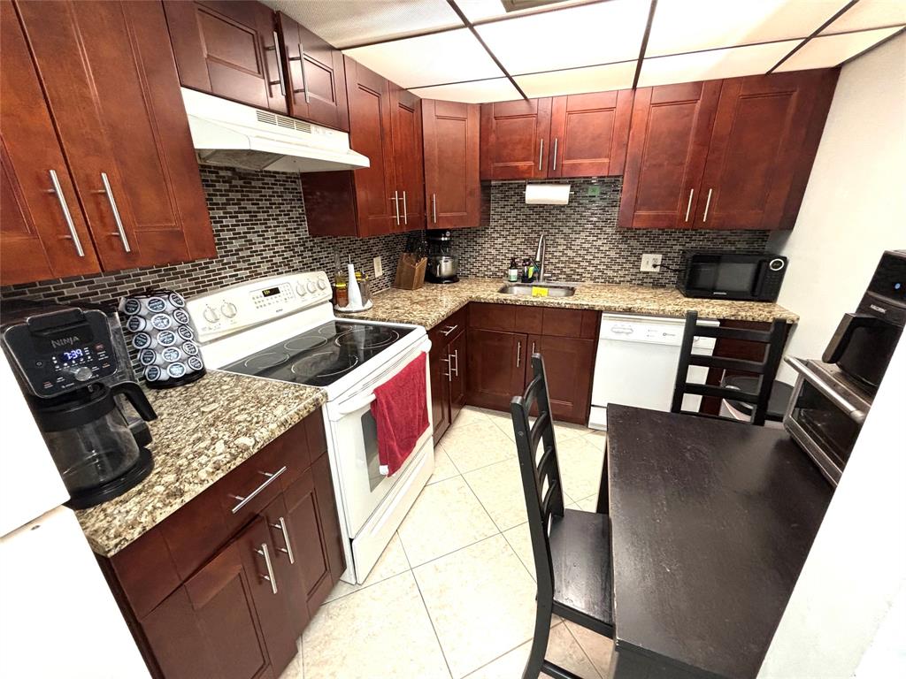 737 Southeast 1st Way, Unit 302 Deerfield Beach, FL 33441 - Photo 6 of 21 a kitchen with stainless steel appliances granite countertop a sink a stove and a microwave