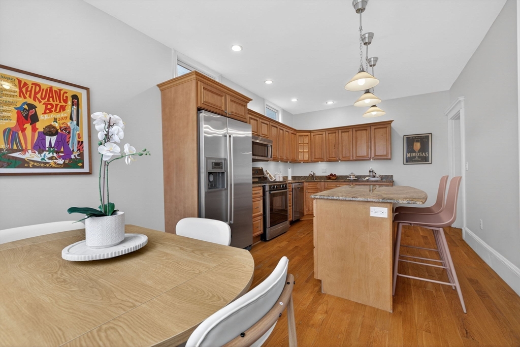 60 Iffley Road, Unit 2 Boston, MA 02130 - Photo 12 of 26 a kitchen with stainless steel appliances kitchen island granite countertop a refrigerator a stove a sink a dining table and chairs with wooden floor