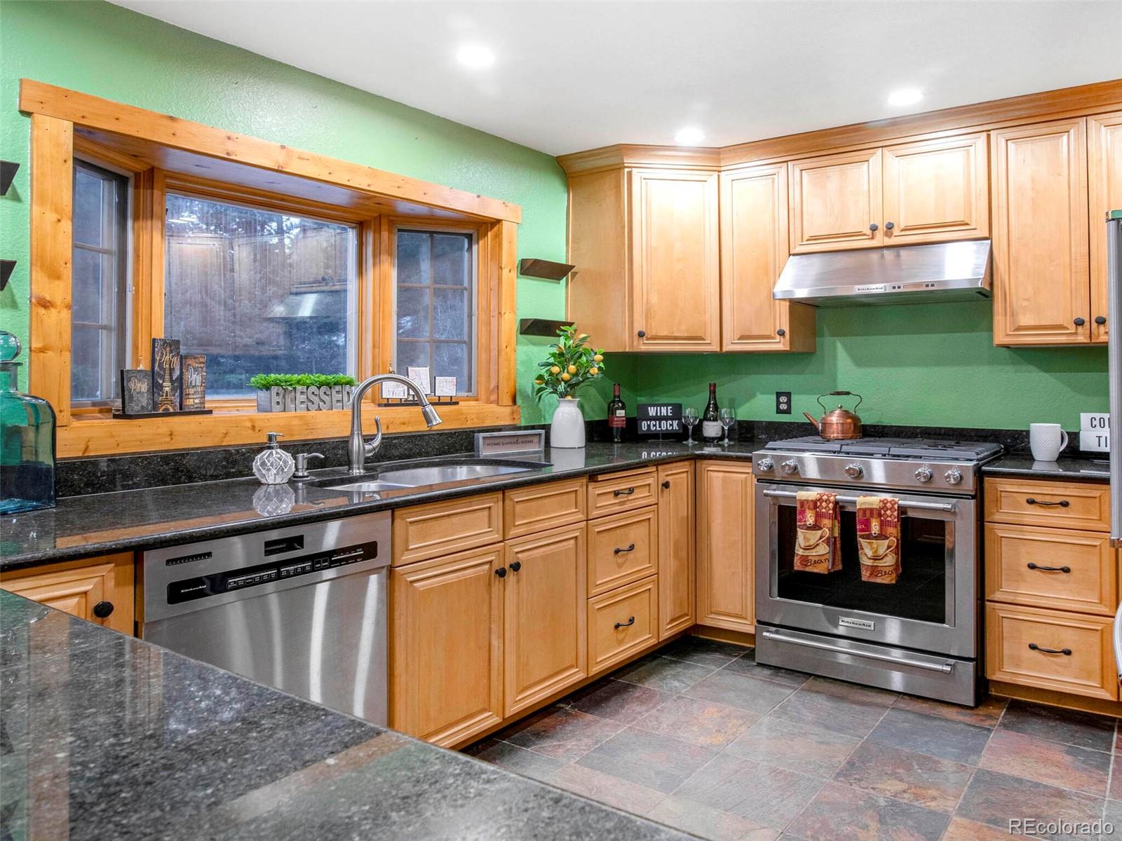 25633 Independence Trail Evergreen, CO 80439 - Photo 9 of 39 a kitchen with stainless steel appliances kitchen island granite countertop a stove and a sink
