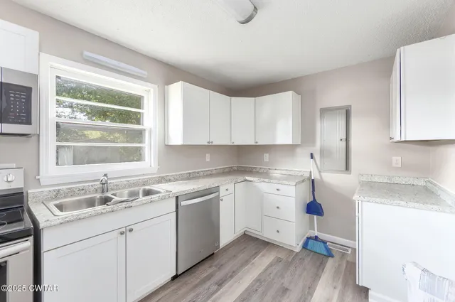 a kitchen with a sink cabinets appliances and a window