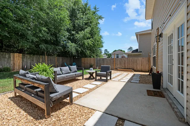 a view of a patio with couches table and chairs with wooden floor and fence