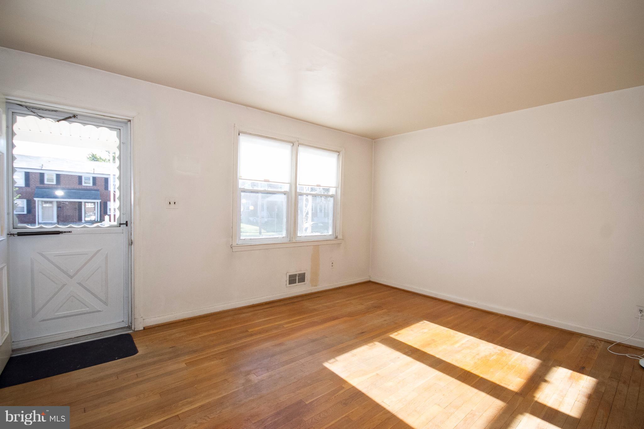 136 Garden Ridge Road Baltimore, MD 21228 - Photo 2 of 25 an empty room with wooden floor and windows