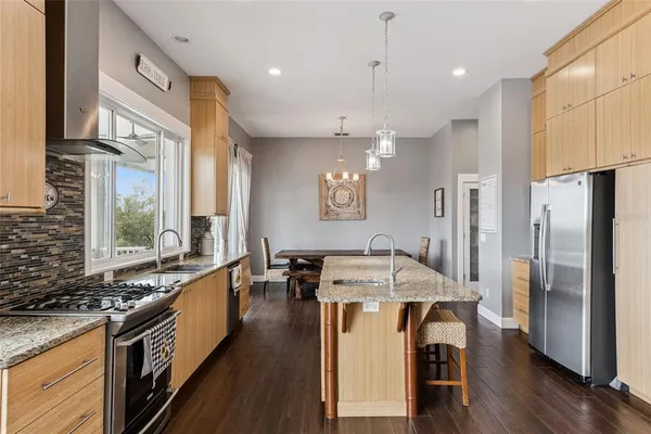 a kitchen with stainless steel appliances granite countertop a sink a stove and a refrigerator