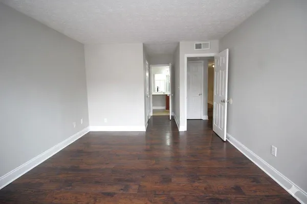 a view of an empty room with wooden floor and closet