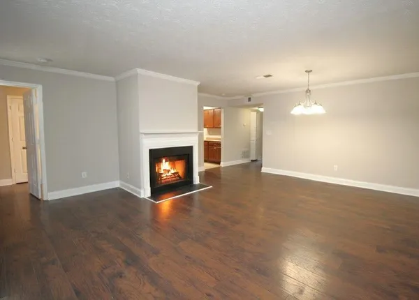 a view of an empty room with wooden floor fireplace and a window