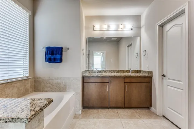 a bathroom with a granite countertop sink a mirror and a bathtub
