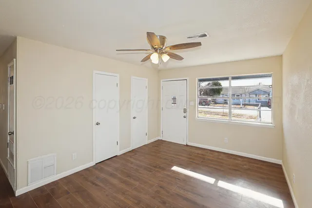 a view of empty room with wooden floor and fan