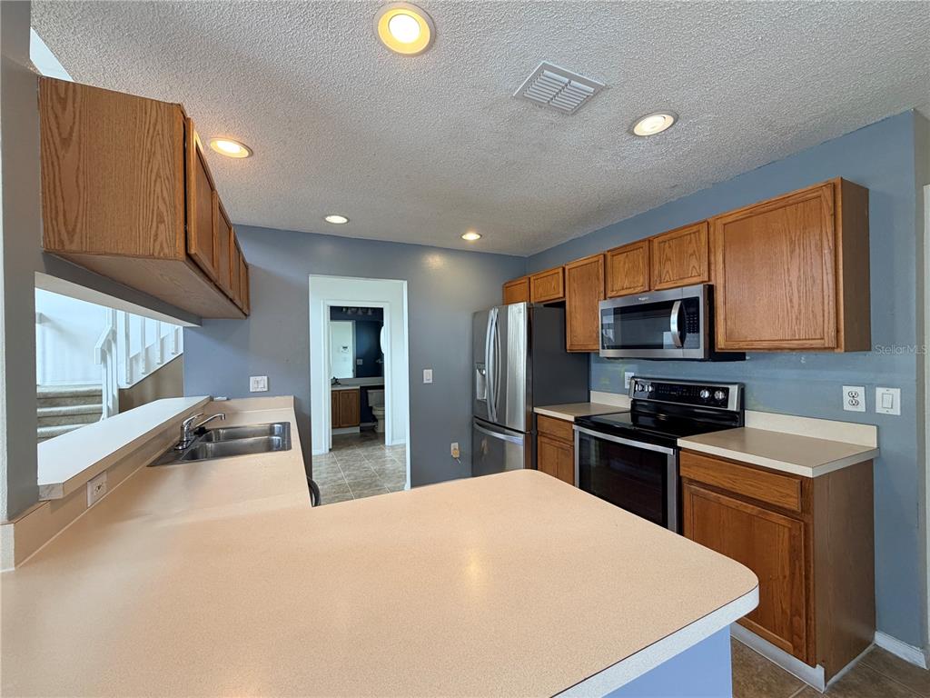 1214 Timberbend Circle Orlando, FL 32824 - Photo 11 of 31 a kitchen with stainless steel appliances granite countertop a sink stove and refrigerator