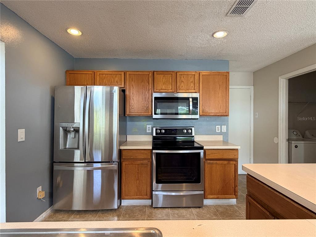 1214 Timberbend Circle Orlando, FL 32824 - Photo 13 of 31 a kitchen with stainless steel appliances granite countertop a refrigerator a stove a sink and a microwave