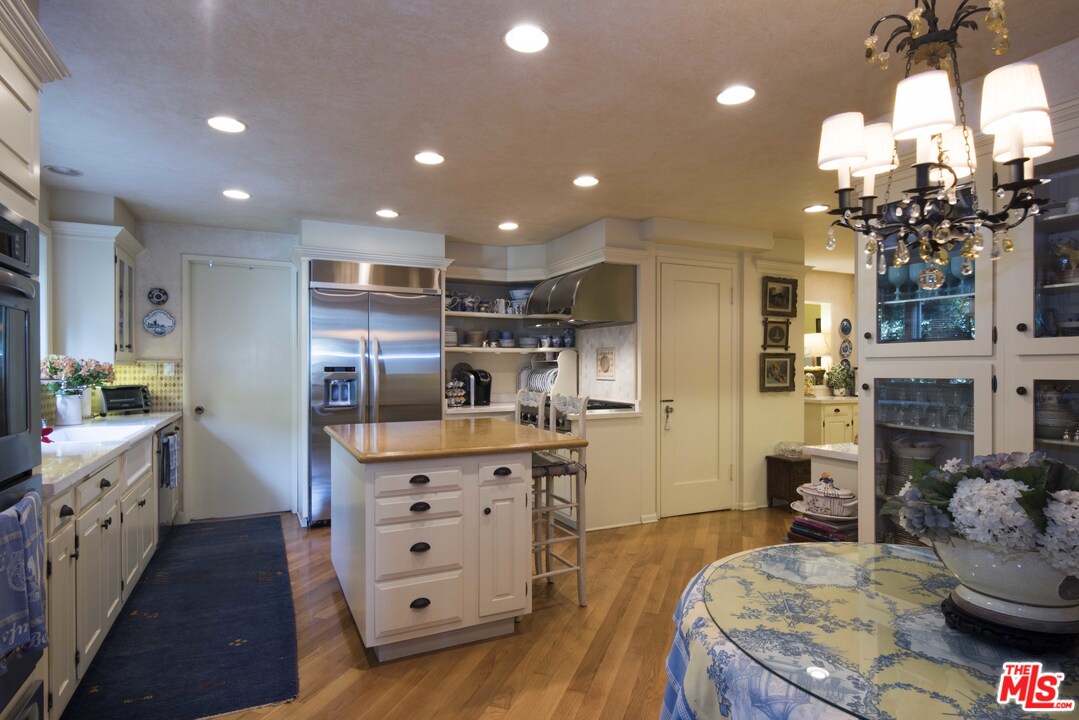 508 South Rimpau Boulevard Los Angeles, CA 90020 - Photo 24 of 48 a large kitchen with stainless steel appliances kitchen island granite countertop a large refrigerator a sink dishwasher and white cabinets with wooden floor