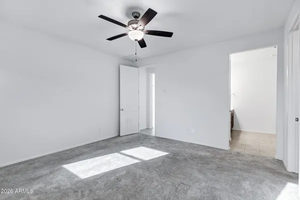 an empty room with a ceiling fan and carpet