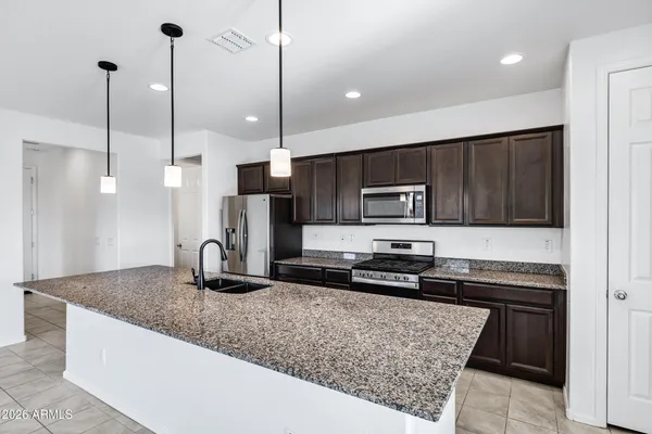 a kitchen with stainless steel appliances granite countertop a sink a stove a refrigerator and a center island