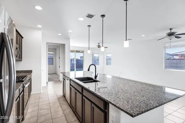a kitchen with kitchen island granite countertop a sink a counter and stainless steel appliances