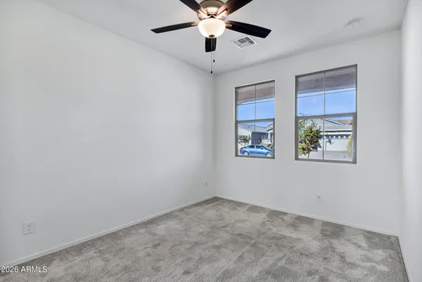 a view of an empty room with window and a ceiling fan