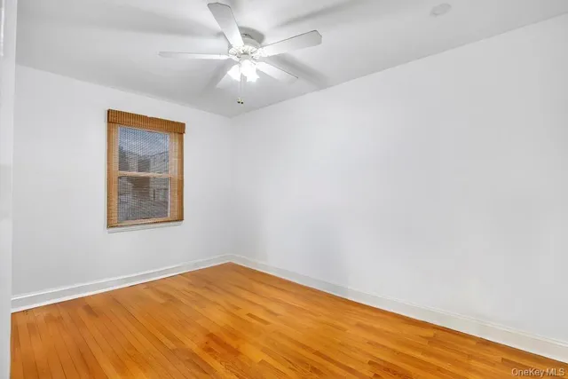 an empty room with a window and ceiling fan