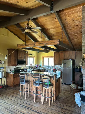 a kitchen with stainless steel appliances granite countertop a table chairs and wooden floor