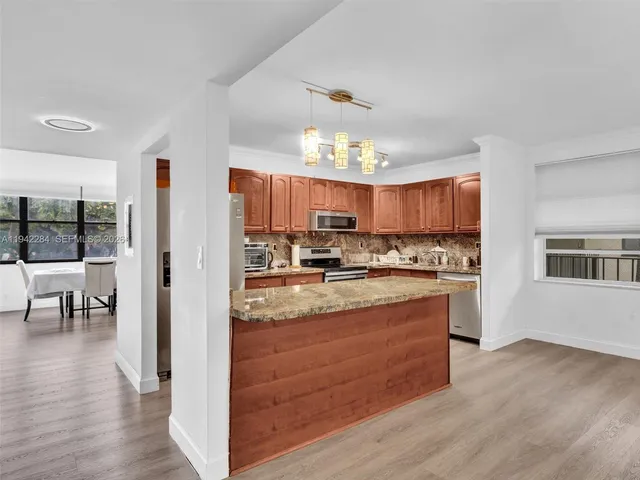 a large kitchen with cabinets wooden floor and stainless steel appliances