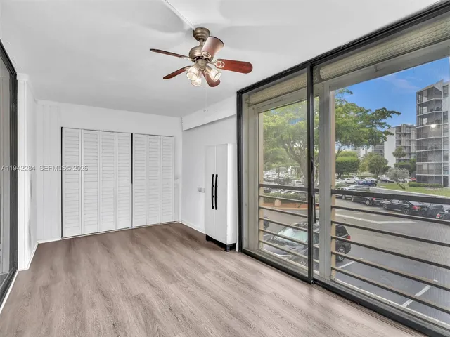 a view of empty room with wooden floor and fan