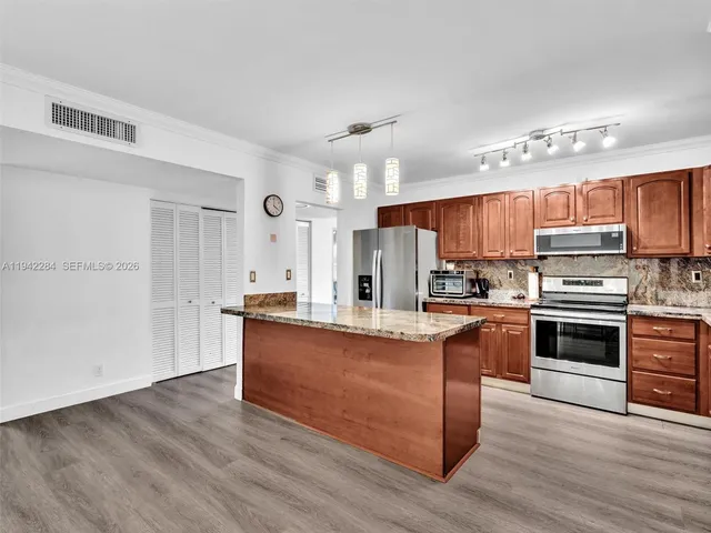 a kitchen with stainless steel appliances kitchen island granite countertop a stove a sink and a refrigerator