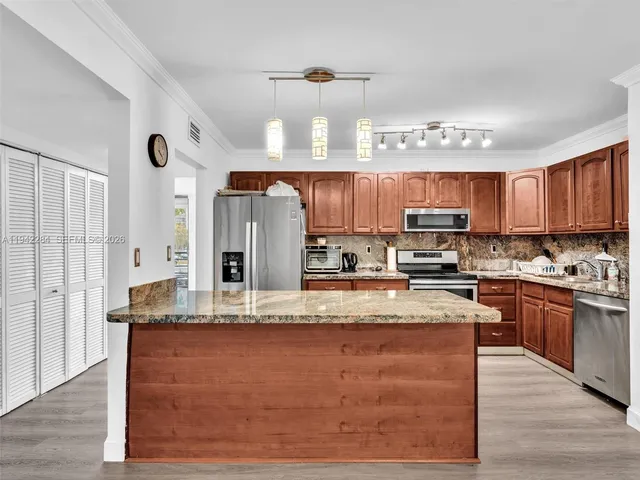 a large kitchen with stainless steel appliances granite countertop a stove refrigerator and cabinets