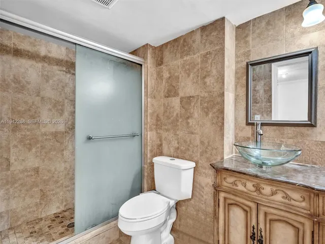 a bathroom with a granite countertop sink a toilet a mirror and shower