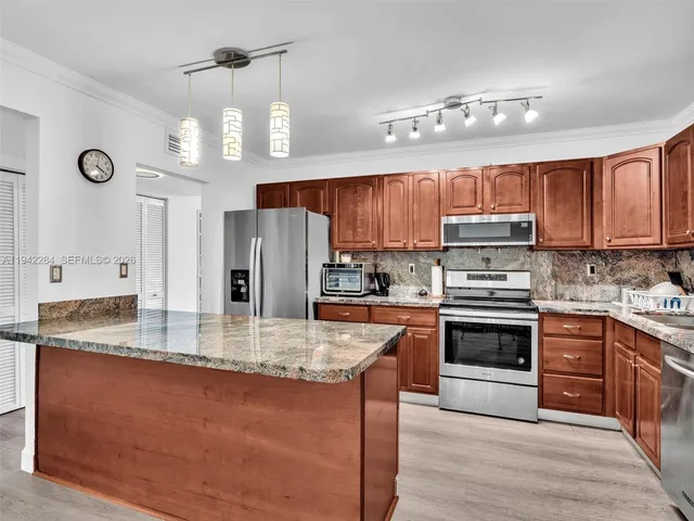 a kitchen with stainless steel appliances granite countertop a stove refrigerator sink and microwave