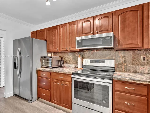 a kitchen with granite countertop wooden cabinets and stainless steel appliances
