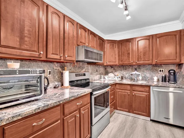 a kitchen with stainless steel appliances granite countertop wooden cabinets a sink and dishwasher a stove top oven with wooden floor