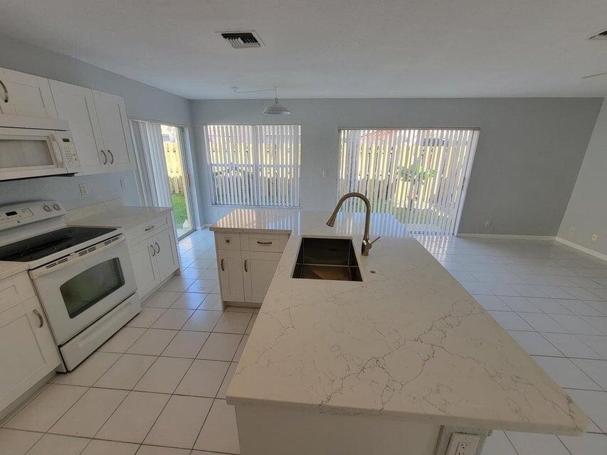 23344 Sunview Way Boca Raton, FL 33428 - Photo 20 of 23 a kitchen with a stove a sink and a refrigerator
