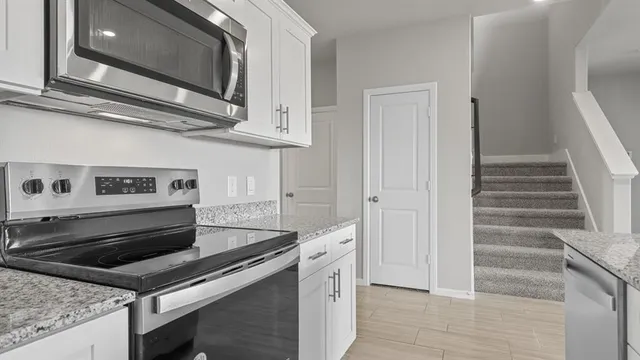 a view of kitchen with granite countertop cabinets and refrigerator