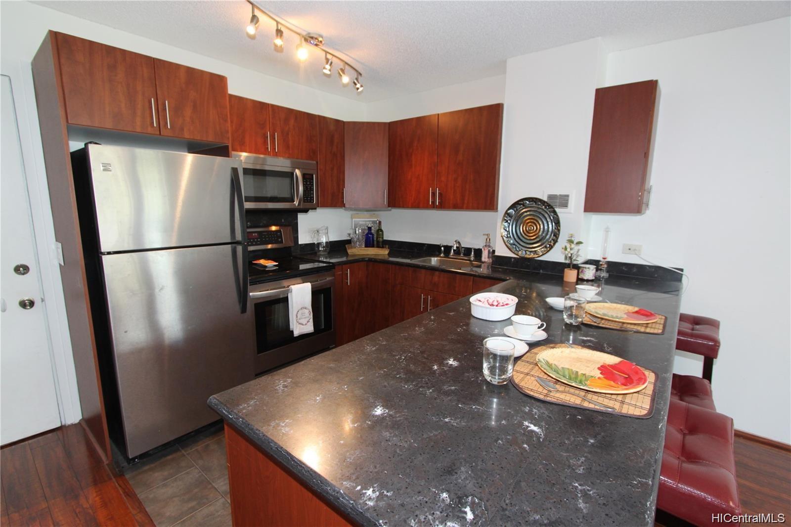 a kitchen with stainless steel appliances granite countertop a refrigerator a sink and a stove with wooden floor