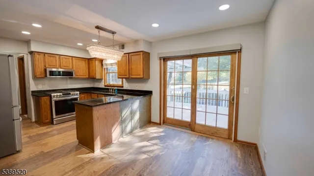 a kitchen with stainless steel appliances granite countertop a stove a refrigerator a kitchen island a table and chairs