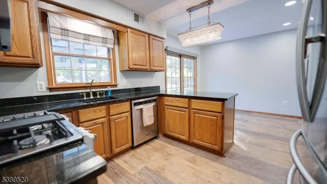 a kitchen with stainless steel appliances granite countertop a refrigerator a stove and a sink