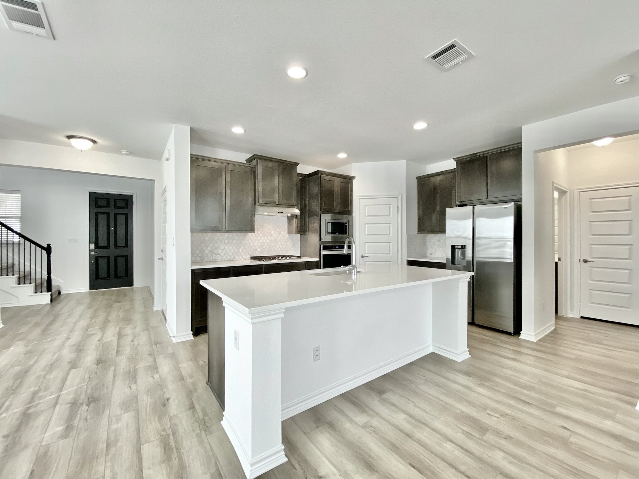 1852 Turtle Bay Loop Leander, TX 78641 - Photo 6 of 38 a large kitchen with kitchen island a sink a center island stainless steel appliances and a living room