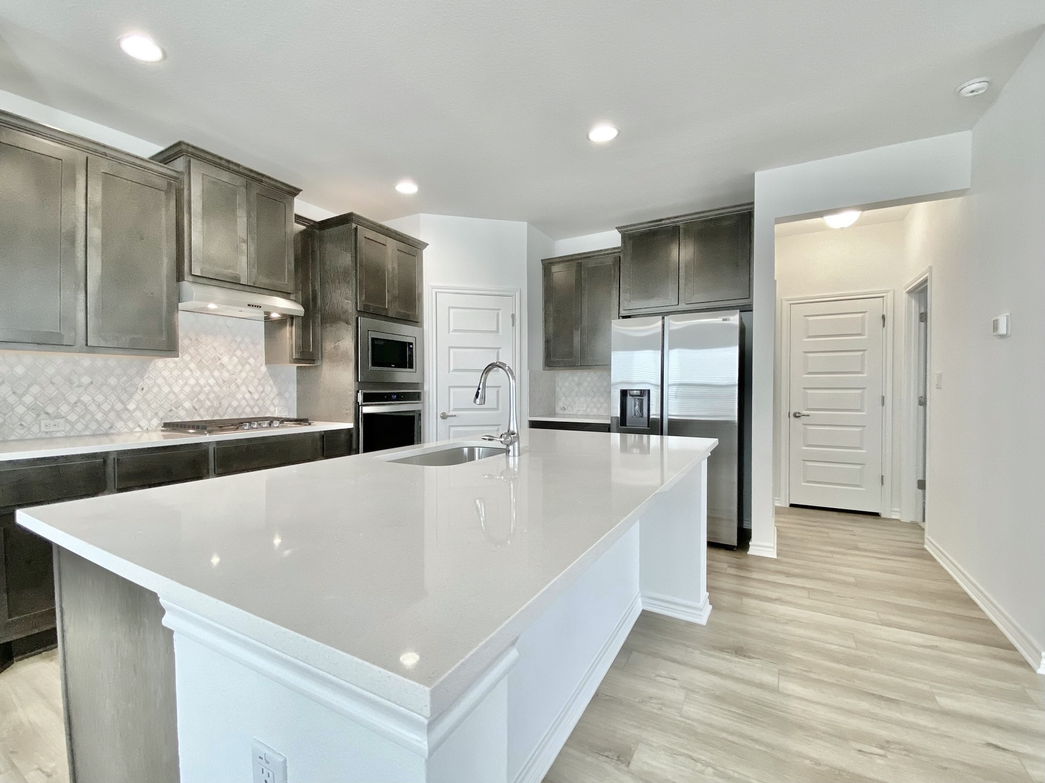 1852 Turtle Bay Loop Leander, TX 78641 - Photo 8 of 38 a large white kitchen with kitchen island a sink stainless steel appliances and cabinets