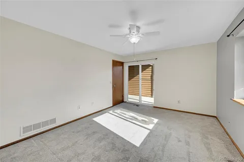 an empty room with chandelier fan and windows