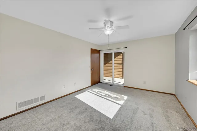 an empty room with chandelier fan and windows