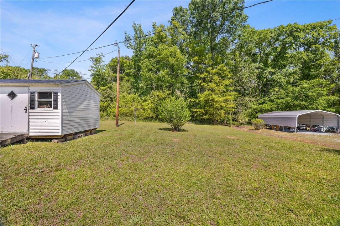 309 East Hampton Avenue Honea Path, SC 29654 - Photo 21 of 23 Expansive outdoor area with a useful storage shed and a covered carport for vehicles.