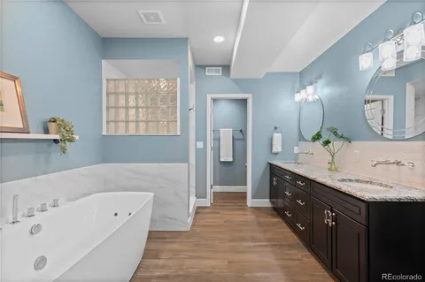 a spacious bathroom with a tub double sink and mirror