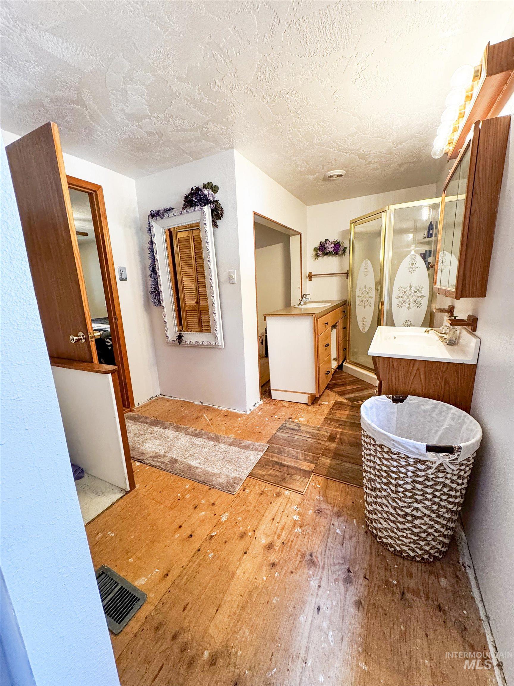 4482 Council Cuprum Road Council, ID 83612 - Photo 13 of 45 Full bath featuring hardwood / wood-style floors, a shower stall, vanity, and a textured ceiling