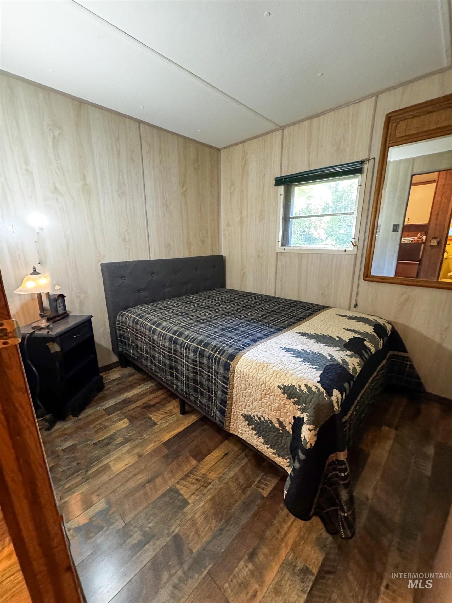 4482 Council Cuprum Road Council, ID 83612 - Photo 17 of 45 Bedroom featuring dark wood-type flooring and wood walls