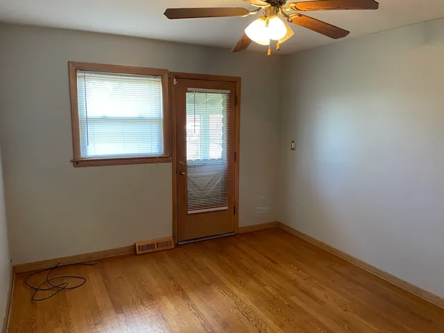 an empty room with wooden floor fan and windows